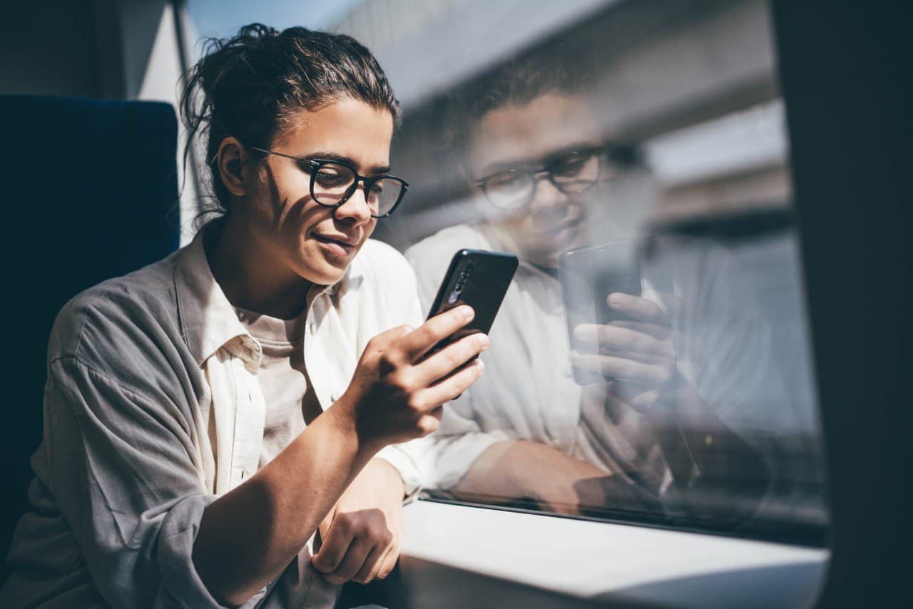 Commuter on train using the TicketPlus+ app – manage your Deutschlandticket comfortably via smartphone